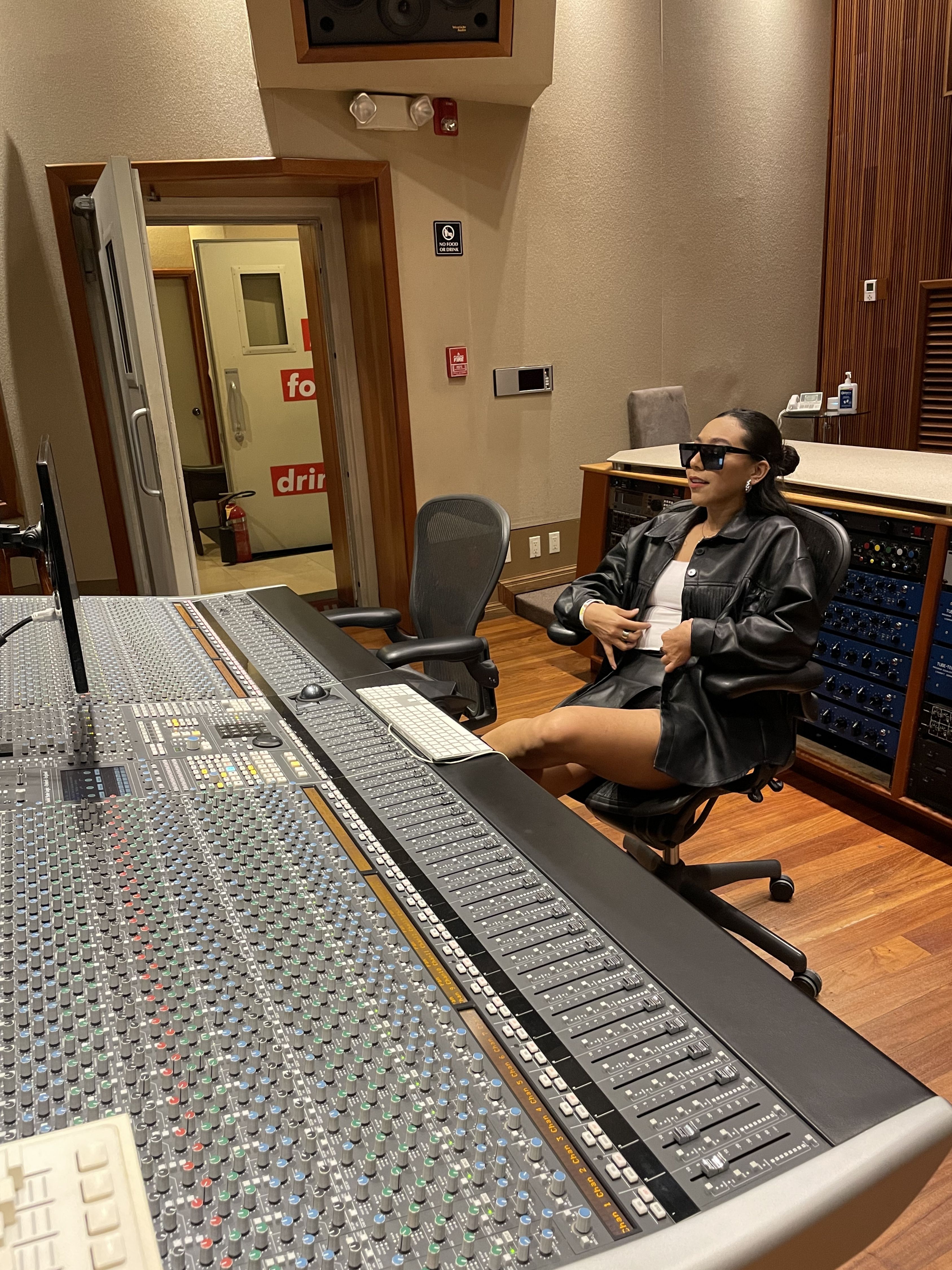 Alyna junto a la consola de un estudio de grabación